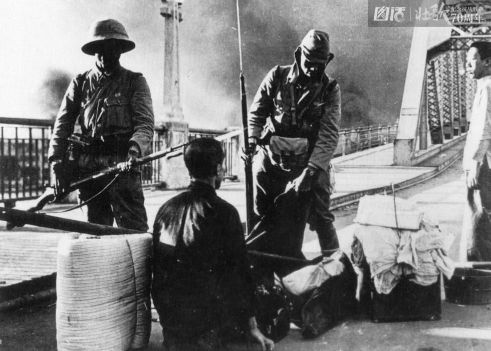 图为1938年，日军占领广州后，在海珠桥头盘查过往行人。这位中国男子因携带大批行李而被勒令下跪。