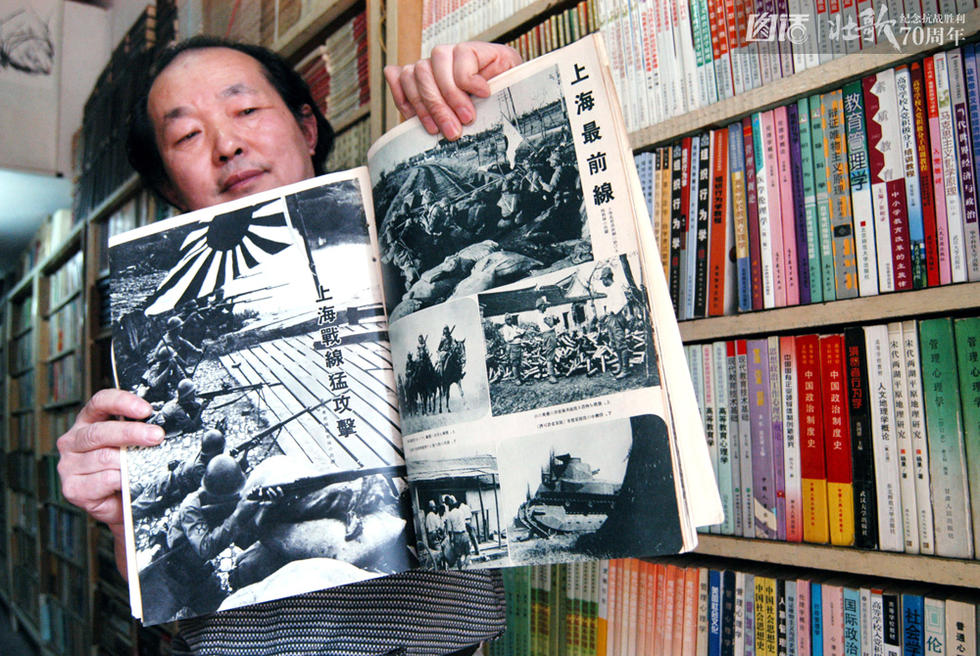 图为2004年，武汉市民吴恒熙展示两本日本侵略中国战时画册—《支那事变写真帖》和《日支战线实写特辑号》。