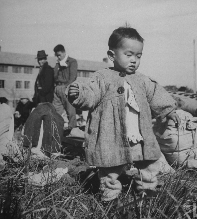 年幼的日本孩子站在家庭行李旁等候遣返回到日本。