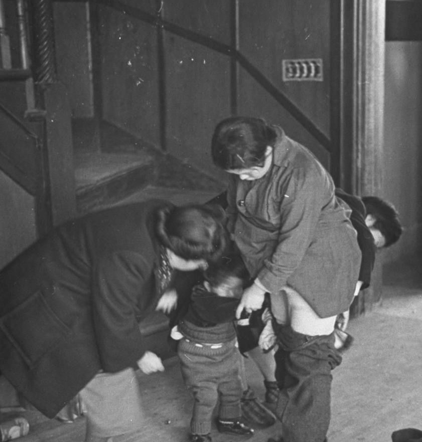 中国海关工作的妇女，检查被遣返的日本妇女和儿童服装并寻找违禁品。