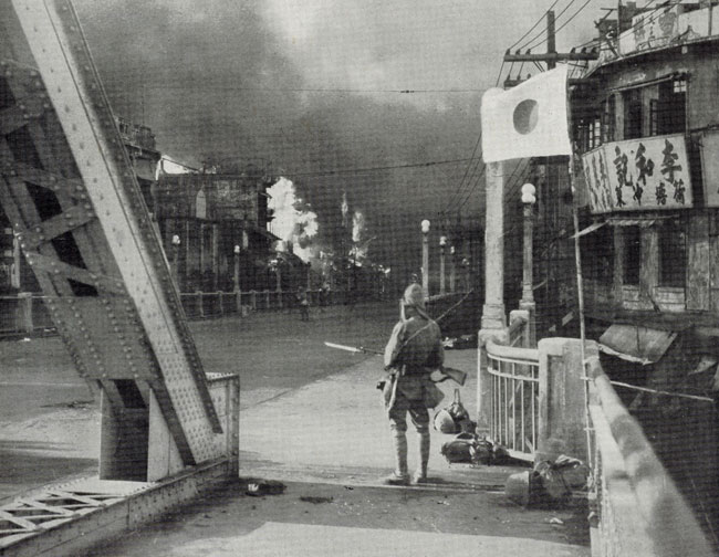 一名日军士兵正在凝望熊熊燃烧的广州市街。