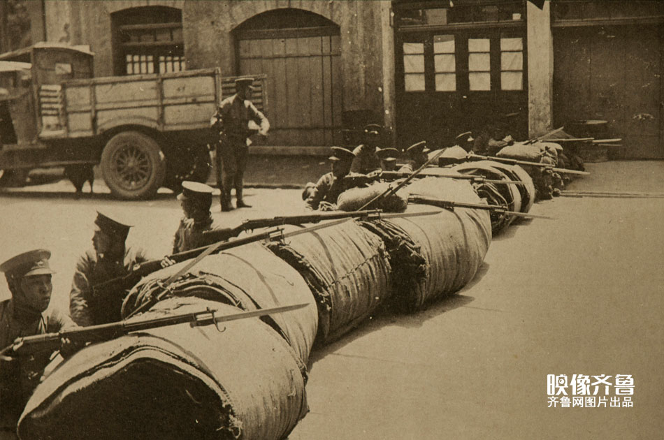 1928年4月中下旬，进入济南的日军在邻接济南城的济南商埠以纬四路为中心线，划为东西两个警备区，构筑工事。图为日军士兵在济南街头布置防御攻势。