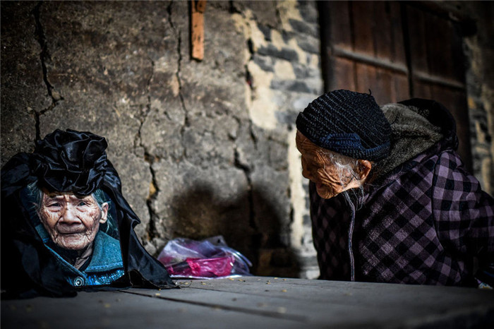 图为2014年12月2日，韦绍兰看着何玉珍老人的遗像不停砸吧嘴巴，呢喃了很久都不愿离去。