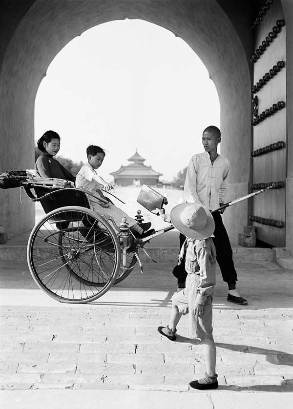 坐在黄包车里的母子接过一个手提袋。中国，1930年