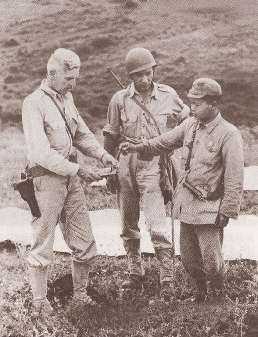 7月23日，一位美军顾问正通过翻译向一位中国士兵讲解发烟弹（美军手持）及信号枪（中国士兵身背）的使用方法。