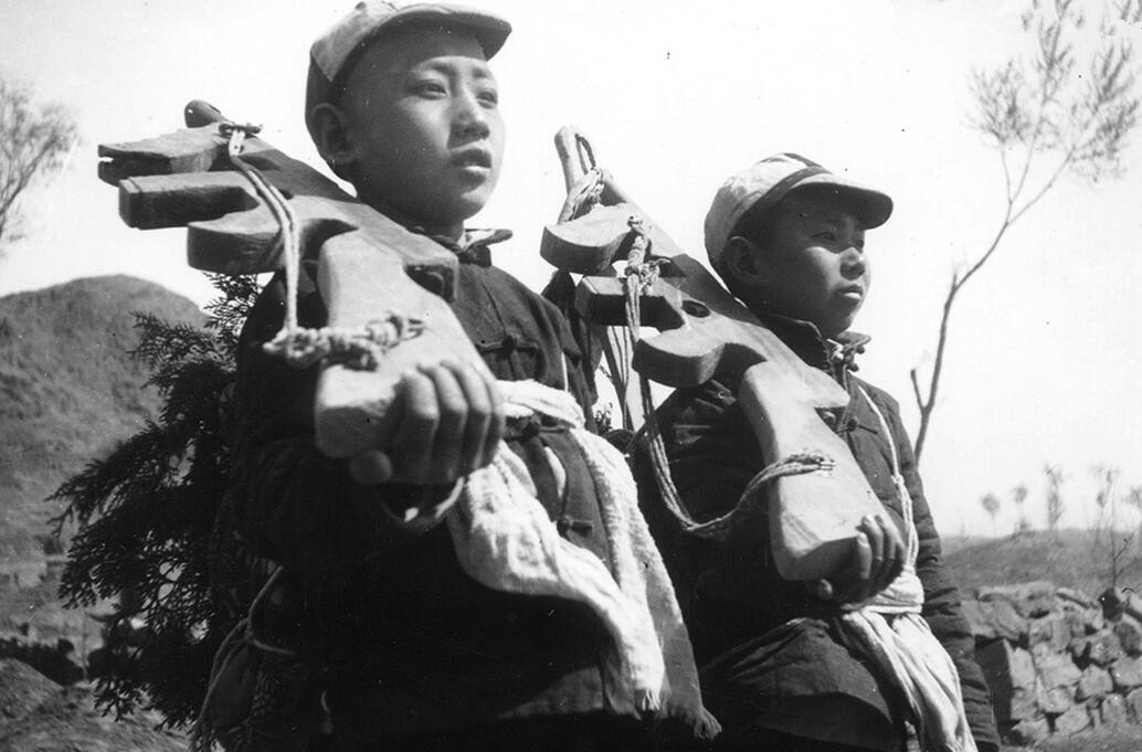图为晋察冀边区的两个儿童团成员扛着木头枪放哨。 