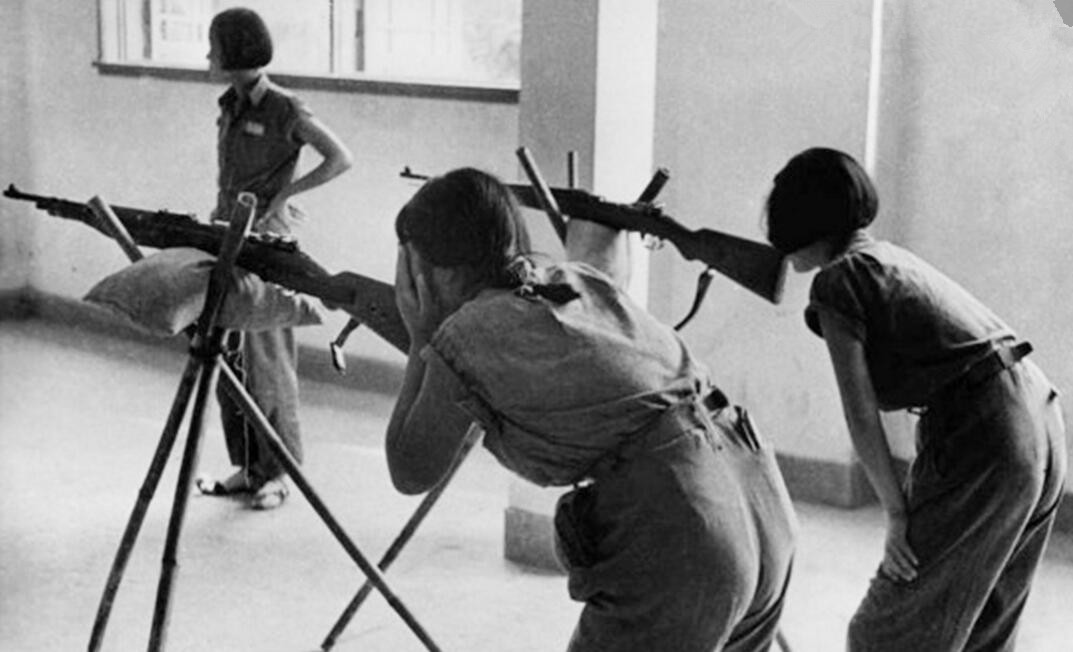 图为在一间室内射击场里，两名年轻女子用三角架上的步枪练习瞄准，提高射击技术。 